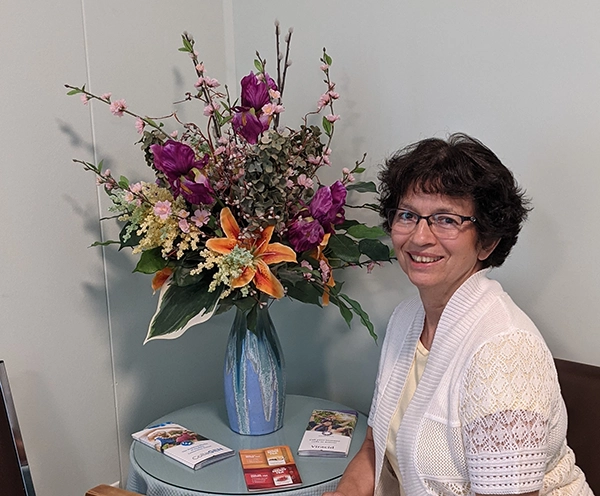 Elia Acuna Holistic Health Practitioner Holistic Health Practitioner Elia Acuna sitting next to a bouquet of flowers. Trigger Point. Bioimpedance Analysis